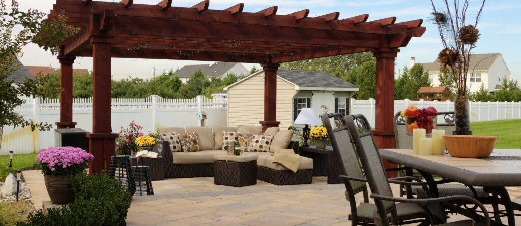 Artisan style wooden pergola with outdoor seating area and a nearby dining area.