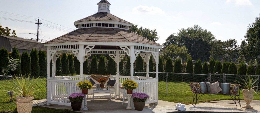 White vinyl gazebo with a pagoda and a cupola, and near a pool.
