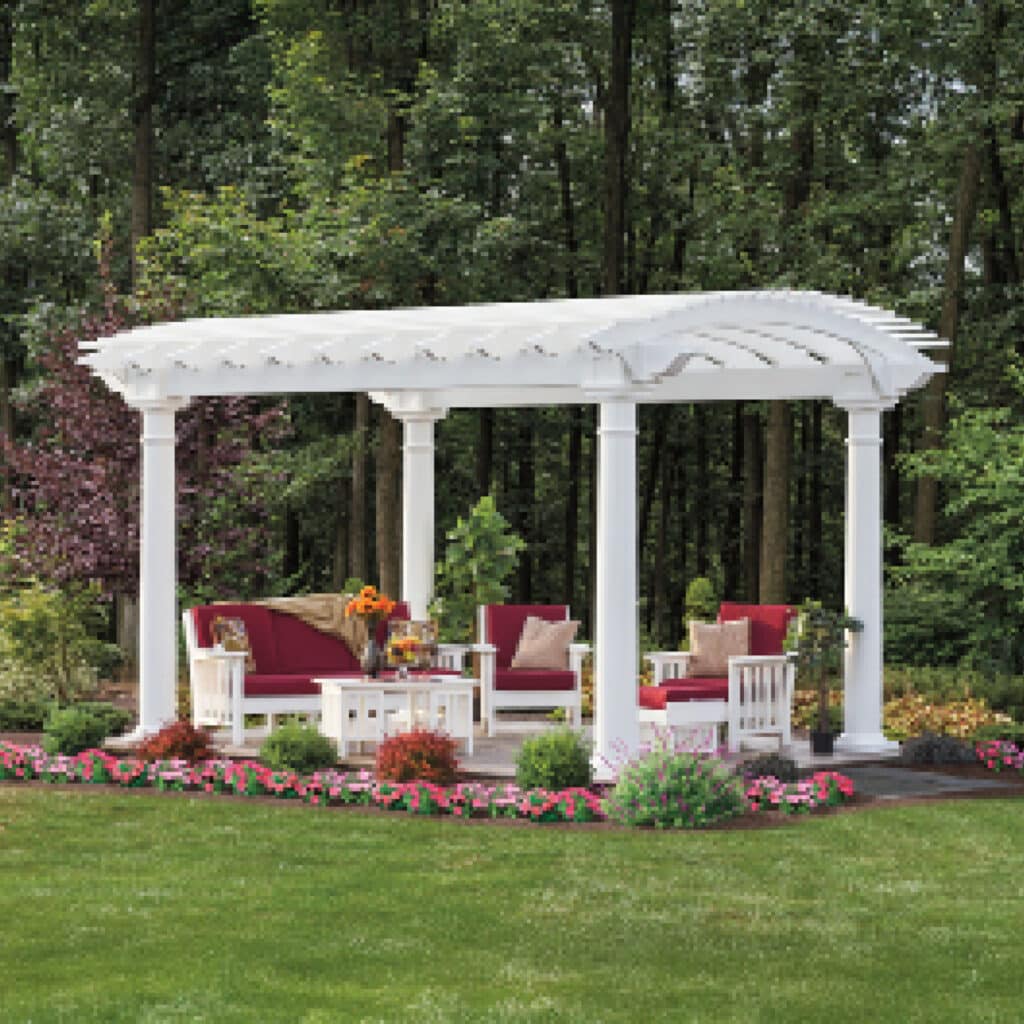 a white pergola with red cushions and a table in a garden