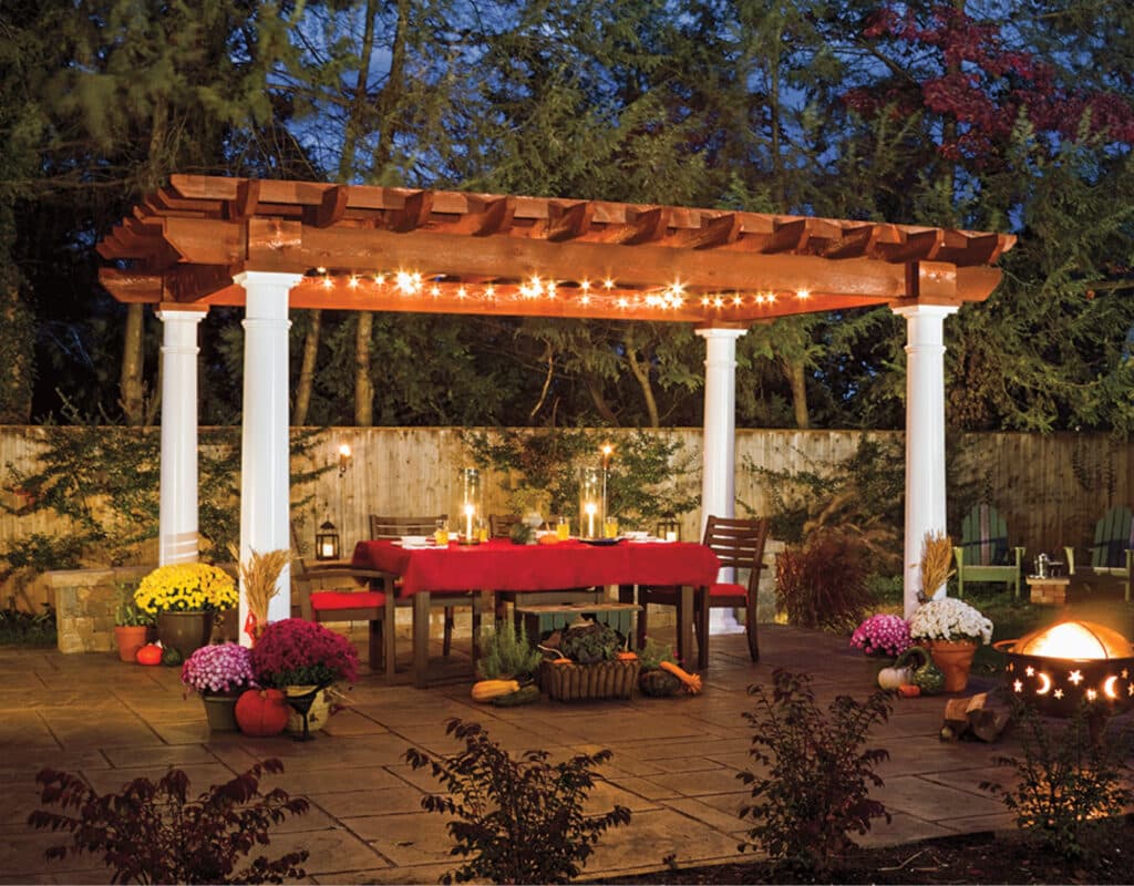 a table with lights on a patio with a pergola and white columns