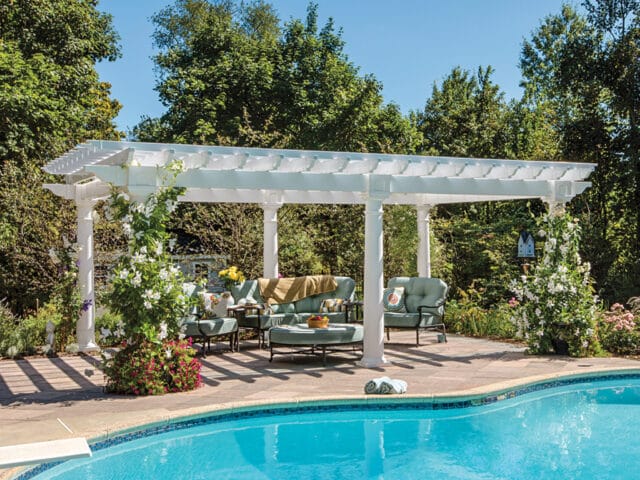 a pool with a white pergola and chairs