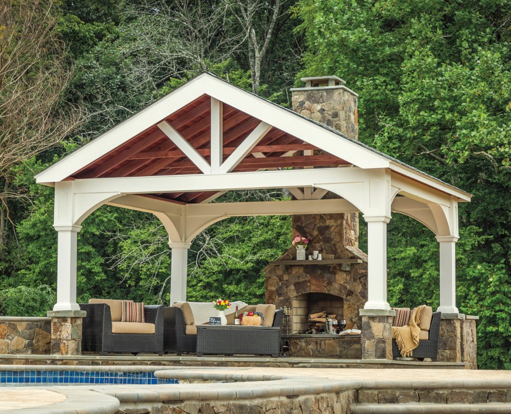 a white covered patio with a fireplace and a pool and a large pavilion