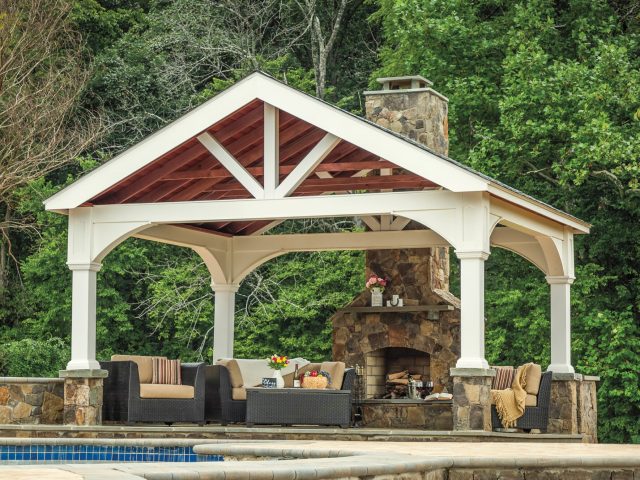 a white covered patio with a fireplace and a pool and a large pavilion