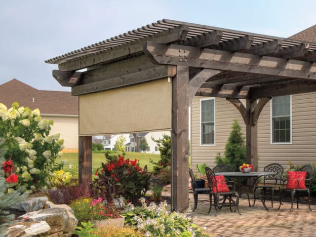 a pergola with shade and patio with a table and chairs